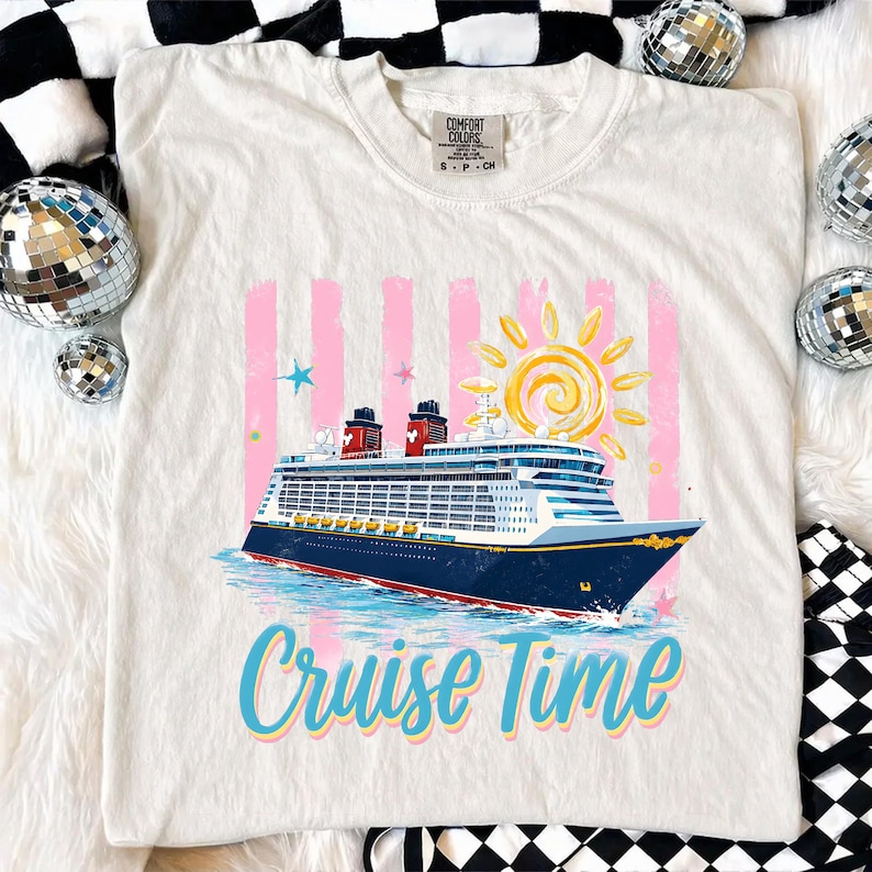 May include: Cream-coloured t-shirt featuring a colourful cruise ship design with the text "Cruise Time." The graphic includes a sun, pink stripes, and stars. The shirt is a Comfort Colors brand.