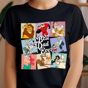 Pu&ograve; includere: T-shirt nera con un collage di personaggi dei cartoni animati e la scritta "Best Dad Ever". Il design include immagini di un leone, un supereroe e altri personaggi.