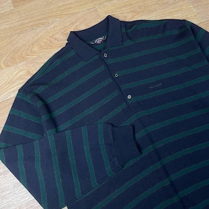 May include: A long-sleeved polo shirt with navy blue and green horizontal stripes. The shirt has a collared neckline with three buttons and a small logo on the chest. The sleeves have ribbed cuffs.