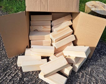 May include: A cardboard box overflowing with natural wood blocks. The blocks are stacked and scattered, showing their smooth, unfinished surface.