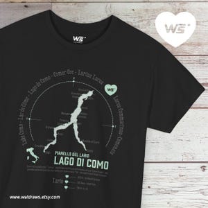 Può includere: T-shirt nero con una mappa del Lago di Como, in Italia, e la scritta "Lago di Como" in verde chiaro. La maglietta presenta anche il testo "Pianello del Lario" e il sito web "waldraws.etsy.com".