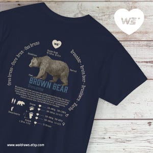 Può includere: T-shirt blu navy con un'illustrazione dettagliata di un orso bruno, etichettata "Brown Bear" e Ursus arctos. Include informazioni sull'orso, misure in cm e kg, e il sito web "www.waldraws.etsy.com".