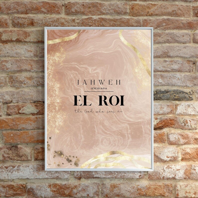 Op de afbeelding: Ingelijste kunstdruk met een zachtroze en gouden abstract ontwerp. De tekst luidt "JAHWEH" en "EL ROI the God who sees me" in zwarte letters. De lijst is wit.