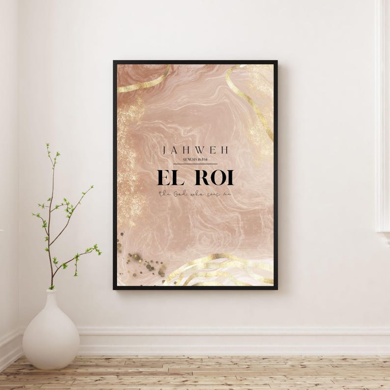 Op de afbeelding: Een ingelijste kunstdruk met een zwarte rand. Het kunstwerk heeft een roze en gouden abstract ontwerp met de woorden "JAHWEH EL ROI" in zwarte tekst. De print hangt aan een witte muur.