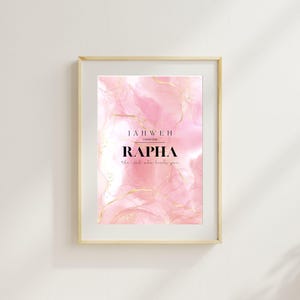 Puede incluir: Impresión artística enmarcada con un fondo de acuarela rosa y detalles dorados. Los textos "JAHWEH" y "RAPHA" se muestran en negro, con la frase "el que te sana" debajo. La obra de arte está dentro de un marco de madera clara.