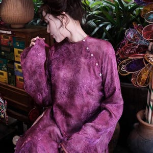 Puede incluir: Vestido magenta de manga larga con estampado floral. El vestido tiene cuello mandar&iacute;n y se abrocha con peque&ntilde;os botones blancos. Las mangas son anchas y fluidas. La tela parece ligera y semitransparente.