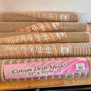 May include: Five rolls of mesh fabric wrapped in clear plastic. Four rolls are labeled Jute Poly Mesh 21 inches by 10 yards. The bottom roll is labeled Cotton Drift Mesh 21 inches by 10 yards with a pink rectangular label featuring white text.