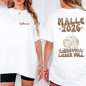 Könnte beinhalten: Weißes T-Shirt mit dem Namen "Katharina" in brauner Schrift auf der Vorderseite. Auf der Rückseite befinden sich "MALLE -2026-" im Leopardenmuster, zwei Bierkrüge und der Schriftzug "HANNOVER LIEBER VOLL" in Braun.