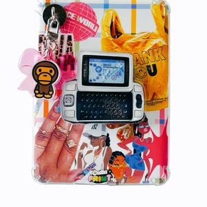 Puede incluir: Una funda de teléfono rectangular transparente con un collage de gráficos coloridos que incluye una bolsa de plástico amarilla, un teléfono T-Mobile Sidekick e ilustraciones de personas. Un lazo rosa y un dije de mono cuelgan arriba a la izquierda.