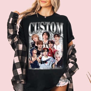 May include: Black t-shirt with a silver graphic of the word "CUSTOM" and a collage of seven men's faces.