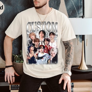 May include: A beige t-shirt with a graphic print of a group of people. The print features the word "CUSTOM" in a silver metallic font. The people in the print are wearing various clothing and have different hairstyles.