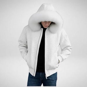 May include: White hooded jacket with a faux fur trim around the hood. The jacket has a textured, crocodile-like pattern and a zip closure. The person in the image is wearing a black top and blue jeans.