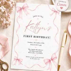 Peut inclure: Une invitation blanche ornée de nœuds et de rubans roses à l'aquarelle. Le texte indique "Katty's FIRST BIRTHDAY!" avec les détails de l'événement. Un stylo doré et un ruban rose sont à côté de l'invitation. L'invitation est modifiable dans Canva.
