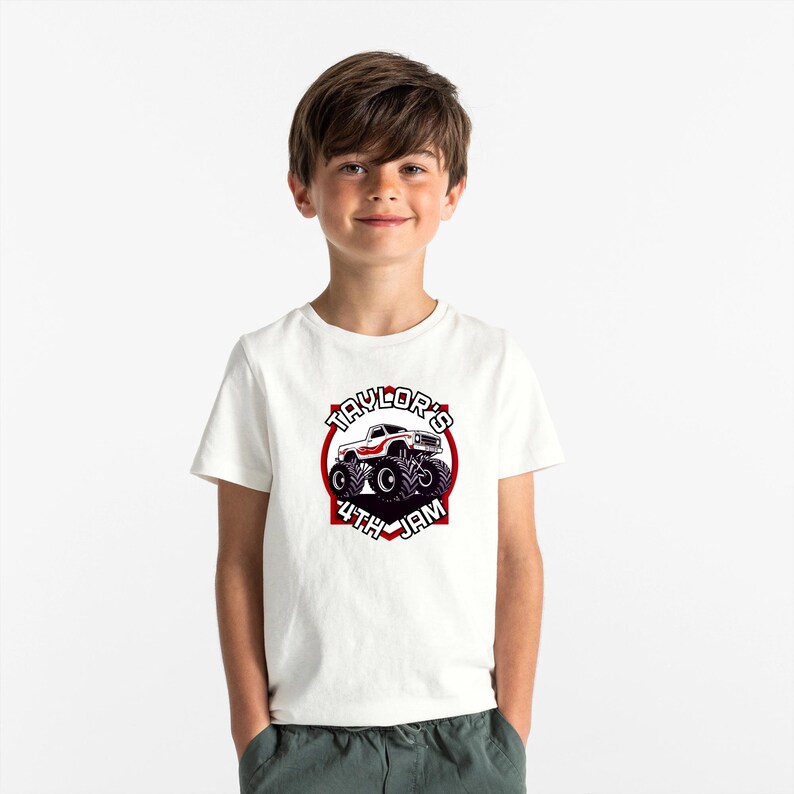 以下が含まれることがあります： 白いTシャツに、赤と黒のモンスタートラックのグラフィックがプリントされています。テキストは「Taylor's 4th Jam」です。