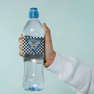 May include: A clear plastic water bottle with a blue cap and a label that says "Taylor's Jam" in a blue and yellow triangle with a checkered pattern.