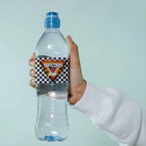 May include: A clear plastic water bottle with a blue cap and a label that says "Taylor's 8th Jam" with a checkered pattern and flames.
