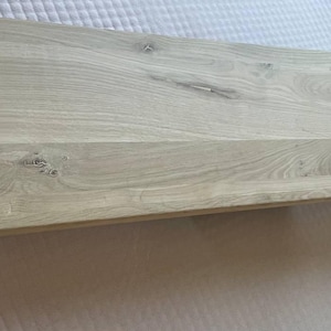 Peut inclure: Une étagère rectangulaire en bois clair avec un grain de bois visible. L'étagère est de couleur gris clair et semble être faite de plusieurs planches de bois. L'étagère est probablement pour la décoration intérieure ou le stockage.