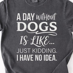 Op de afbeelding: Donkergrijs t-shirt met de tekst "A DAY WITHOUT DOGS IS LIKE... JUST KIDDING. I HAVE NO IDEA." Het shirt heeft opgerolde mouwen en een ronde hals. De merknaam "orvix" staat onderaan.