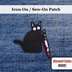 Puede incluir: Parche de gato negro con ojos blancos y un cuchillo con detalles de sangre roja. El parche es de tipo termoadhesivo o para coser. El texto "Iron-On / Sew-On Patch" está en la parte superior. También se incluye un cupón.