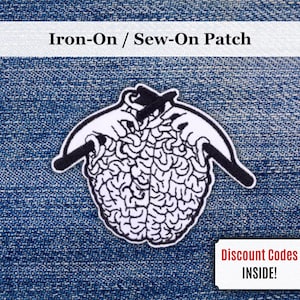 Puede incluir: Un parche para planchar o coser con un diseño en blanco y negro de manos tejiendo un cerebro. El parche está sobre un fondo de mezclilla azul. El texto en la parte superior dice "Iron-On / Sew-On Patch". Se ve un cupón pequeño.