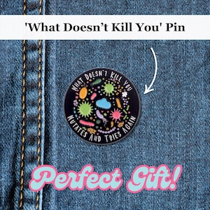 Pode incluir: Um alfinete redondo preto com o texto "What Doesn't Kill You Mutates And Tries Again" em branco. O alfinete apresenta ilustrações coloridas de vários microrganismos. O alfinete é exibido em um fundo de ganga.