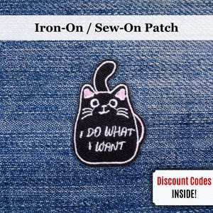 May include: Black cat iron-on patch with the text "I DO WHAT I WANT" in white. The cat has pink ears and a white outline. The patch is on a blue denim background. Includes a small coupon.