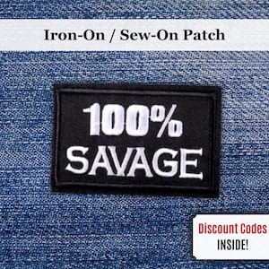 Peut inclure: Un écusson rectangulaire noir à repasser ou à coudre avec les mots "100% SAVAGE" en blanc. L'écusson est affiché sur un fond en denim bleu. Le texte "Iron-On / Sew-On Patch" est au-dessus de l'écusson.