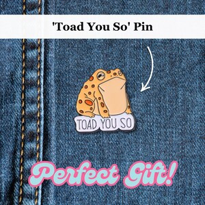 May include: A pin featuring a cartoon toad with orange spots and a beige belly. The pin reads "TOAD YOU SO" on a white background. The pin is set against a blue denim background.