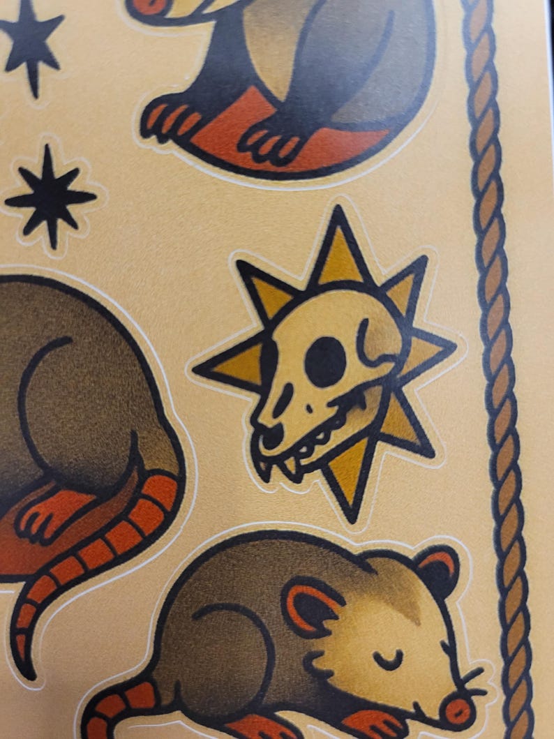 May include: Sheet of stickers featuring opossums, a skull, and starburst designs. The opossums are brown with orange feet and tails. The skull is yellow with a black eye socket. The background is tan.