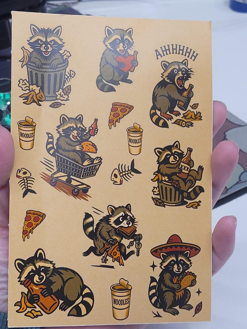 May include: A sheet of raccoon stickers in various poses, holding pizza, beer, and noodles. The raccoons are depicted in a cartoon style, with brown and gray fur and black stripes. Some stickers have the text "AHHHHH" and "NOODLES".