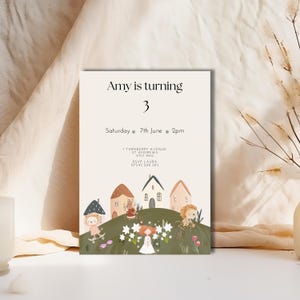 Könnte beinhalten: Eine Geburtstagseinladung mit dem Text "Amy wird 3". Die Einladung zeigt eine Illustration von kleinen Häusern, Blumen und skurrilen Figuren. Datum und Uhrzeit der Party sind ebenfalls angegeben.