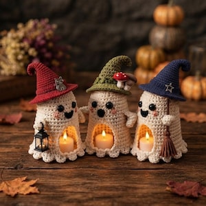 May include: Three crocheted ghost figures in cream yarn, each wearing a pointed hat in red, olive green, or navy blue. The ghosts feature black bead eyes, pink cheeks, and a hollow base containing a small lit candle. Accessories include a tiny lantern, mushrooms, and a broom.