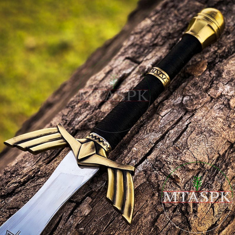 Puede incluir: Una espada de oro y plata con empu&ntilde;adura de cuero negro y pomo de oro. La espada est&aacute; apoyada en un trozo de madera.