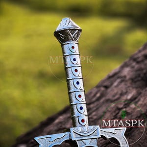 May include: A silver sword with a decorative handle featuring blue and red accents. The handle is adorned with a series of shields with blue and red accents.