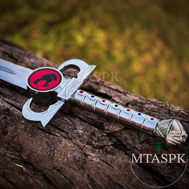 May include: A silver sword with a red and black lion emblem on the hilt. The sword has a silver blade and a silver handle with blue and red accents.