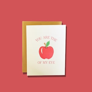 May include: A white card with a red apple and the text "You are the apple of my eye."