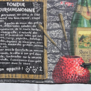 May include: A vintage-style kitchen towel with a black chalkboard design featuring the text "Fondue Bourguignonne" and instructions for preparing the dish. The towel also features a red and white illustration of a fondue pot and a bottle of wine.
