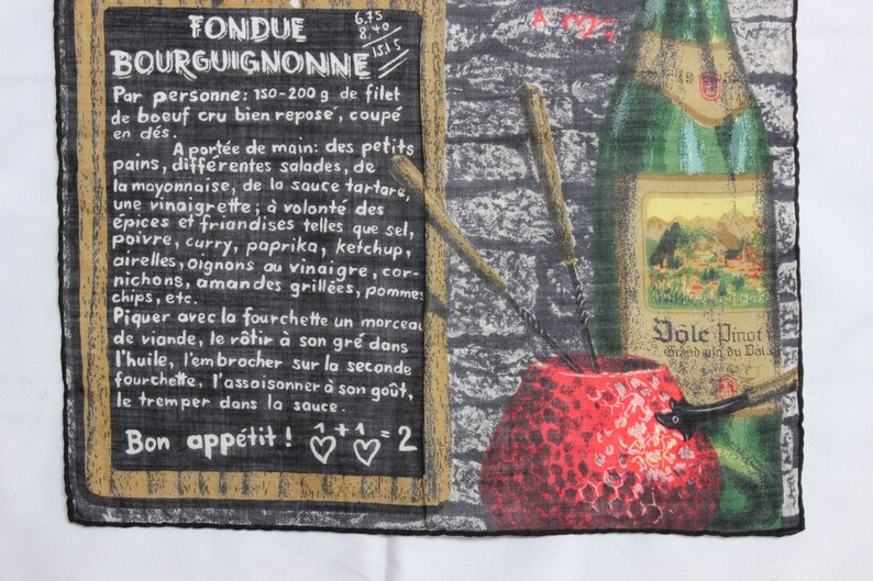 May include: A vintage-style kitchen towel with a black chalkboard design featuring the text "Fondue Bourguignonne" and instructions for preparing the dish. The towel also features a red and white illustration of a fondue pot and a bottle of wine.