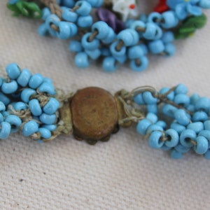 May include: A blue beaded necklace with a brass clasp. The necklace is made of multiple strands of small, round beads.