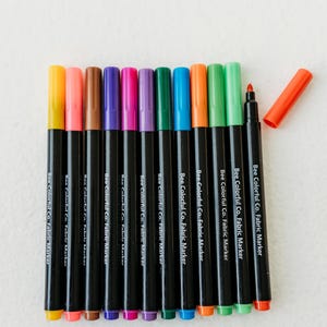 Bee Colorful Co. fabric marker set: 12 rainbow colors. Non-toxic, permanent pens for kids' coloring pajamas, t-shirts, canvas & fabric crafts. Fine tips for detailed designs. Perfect for DIY projects, personalized gifts, and fabric art. ASTM D-4236 certified, ensuring safety for children. Use on clothes, textiles, and apparel for lasting color and creative play. Enhance any project with these easy-to-use, vibrant markers.