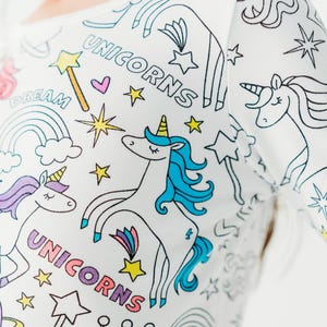 Puede incluir: Camiseta blanca de manga larga con un dise&ntilde;o colorido de unicornio y estrellas. La camiseta tiene las palabras "Unicorns" y "Dream" impresas en ella.