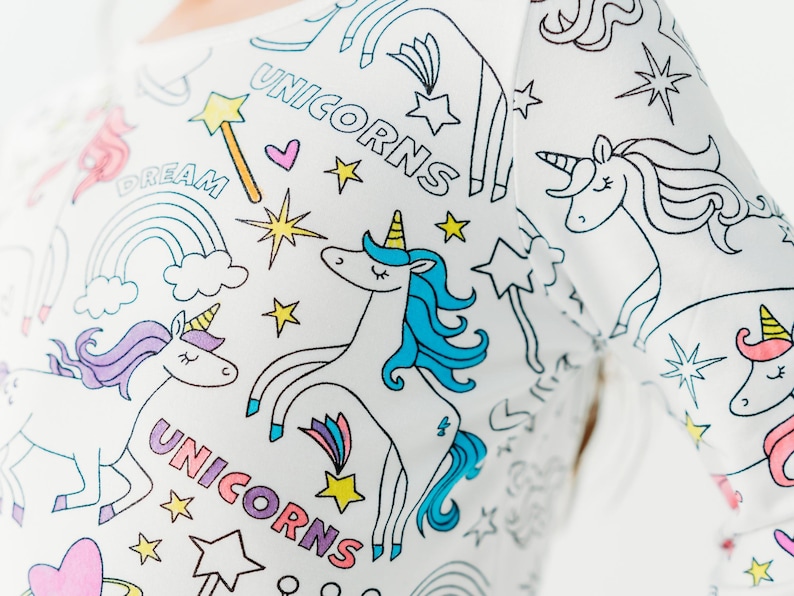 Puede incluir: Camiseta blanca de manga larga con un dise&ntilde;o colorido de unicornio y estrellas. La camiseta tiene las palabras "Unicorns" y "Dream" impresas en ella.