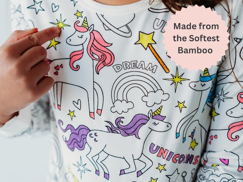 Close-up of unicorn coloring pajamas with 'Made from Softest Bamboo' graphic. Girl points to a colorful design she created.