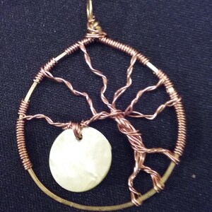 May include: A copper wire tree of life pendant with a white mother of pearl circle in the center.