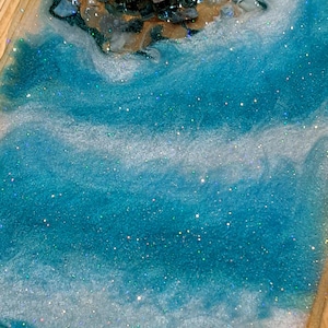 May include: A wooden tray with a resin design in shades of blue and white, reminiscent of ocean waves. The tray is decorated with blue glass stones and a silver dragonfly.