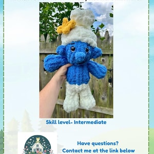 May include: A handmade blue and white Smurf-inspired plush toy, featuring a white hat with a yellow flower. The soft toy has a textured finish. Text on the image reads "Smurfs Inspired" and "3-in-1 Snuggler".