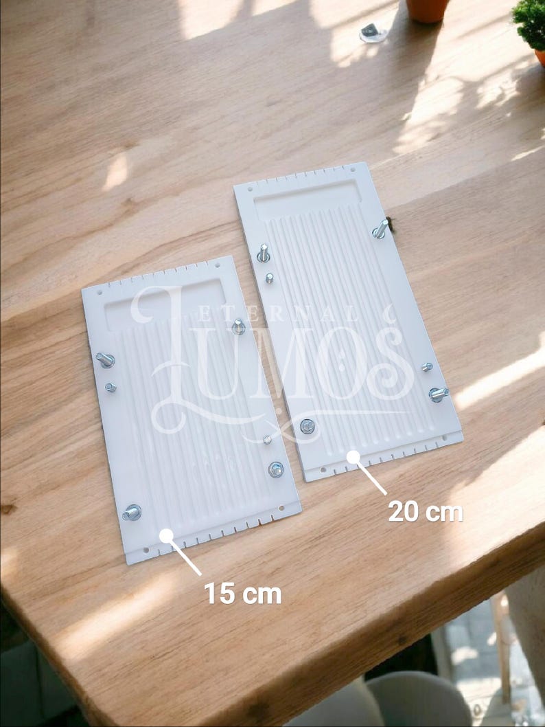 May include: Two white rectangular objects with a ridged surface, secured with screws. One measures 15 cm, the other 20 cm. The text "ETERNAL LUMOS" is visible on the objects. They are placed on a wooden surface.