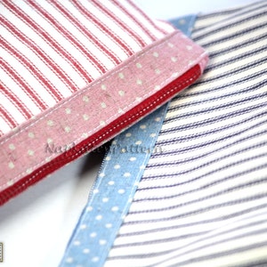 May include: Two fabric zipper pouches with different patterns. One pouch is red and white striped with a pink polka dot trim. The other pouch is blue and white striped with a blue polka dot trim.