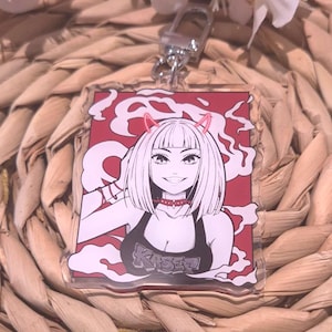 Könnte beinhalten: Ein klarer Acryl-Schlüsselanhänger mit einem lächelnden Anime-Charakter mit rosa Teufelshörnern und einem roten Halsband. Der Charakter trägt ein schwarzes Oberteil mit dem Wort "KASEI" vor einem roten Hintergrund mit weißen rauchartigen Designs. Inklusive Silberverschluss.