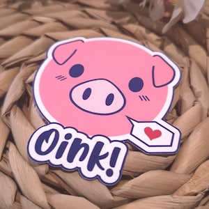 Könnte beinhalten: Ein rosa Schweineaufkleber mit weißem Rand. Das Schwein hat blaue Augen, eine Schnauze und Ohren. Eine Sprechblase mit rotem Herz und dem Wort "Oink!" in blauer Schrift ist angebracht.